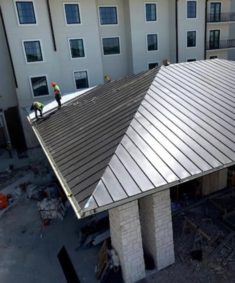 Crew installing standing seam metal roof panels on a commercial project in Rendon